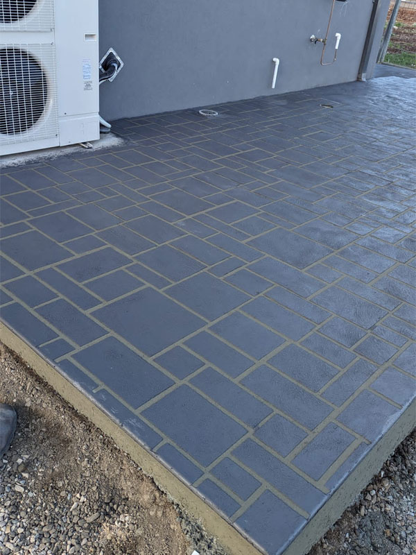 Charcoal paver-pattern stencilled patio beside air conditioning units
