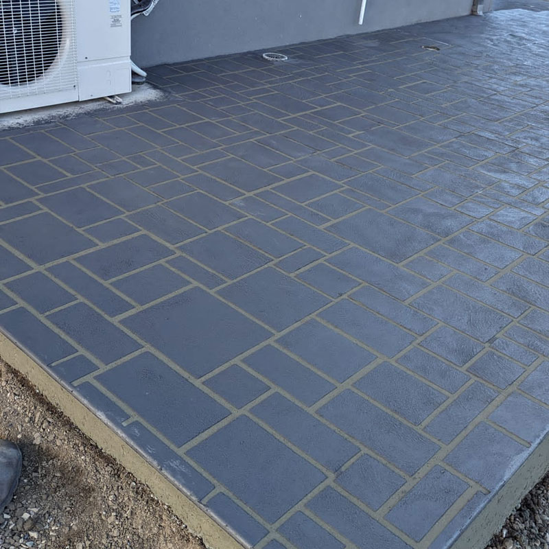 Charcoal paver-pattern stencilled concrete patio beside air conditioning units