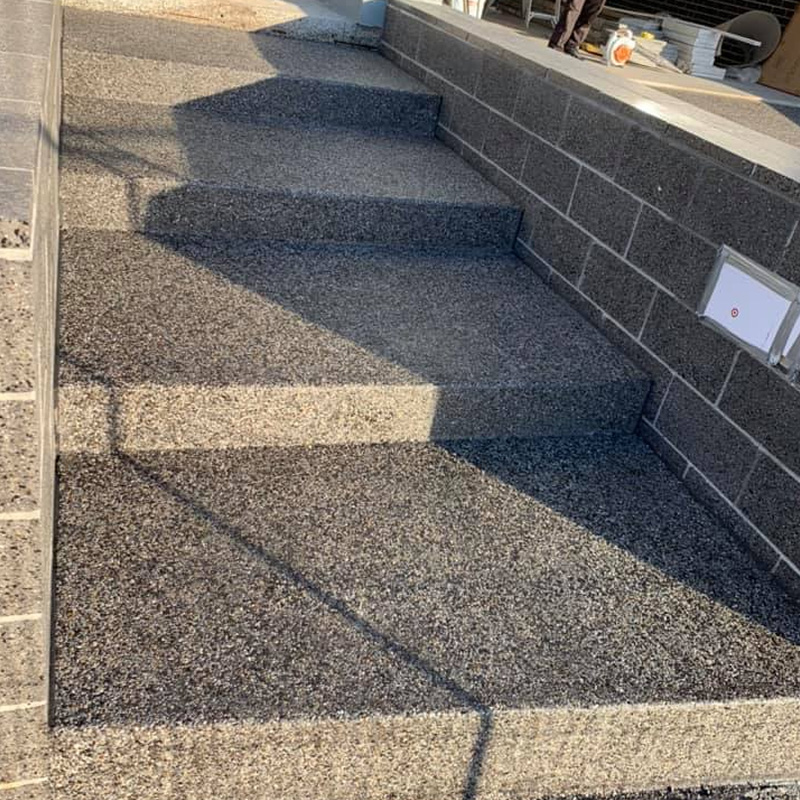Exposed aggregate concrete steps beside a block wall