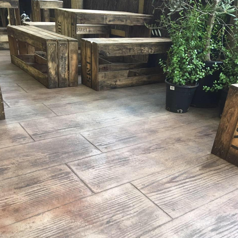 Timber-look stencilled concrete under outdoor timber tables