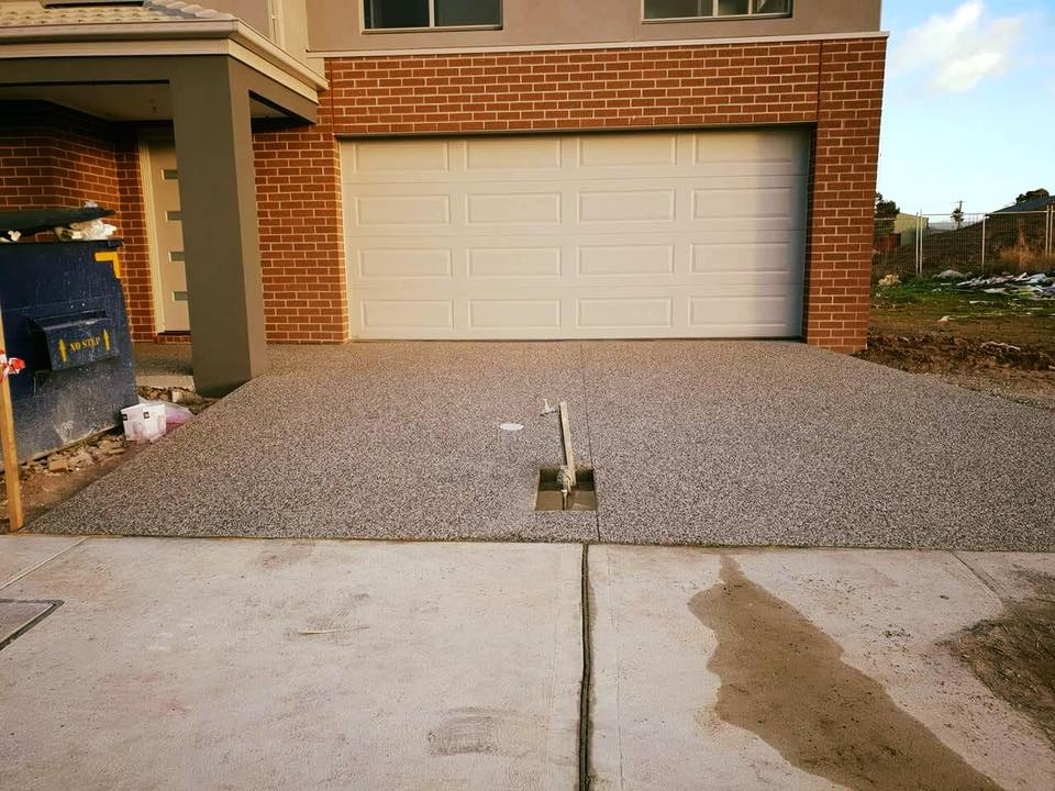 Exposed aggregate driveway in front of a new brick home's garage