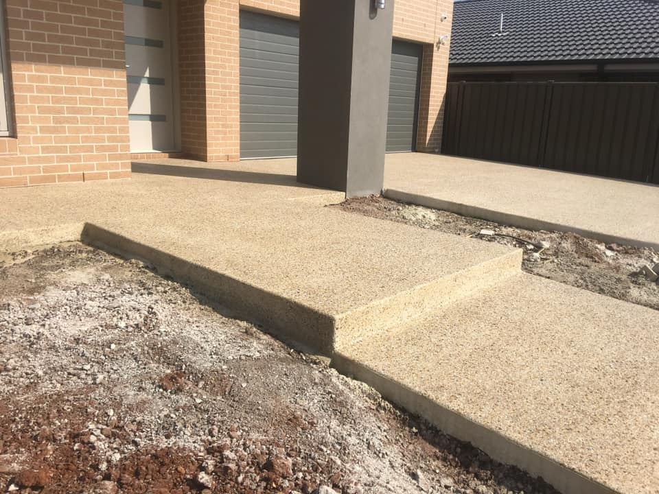 Light exposed aggregate path and step in front of a new brick home