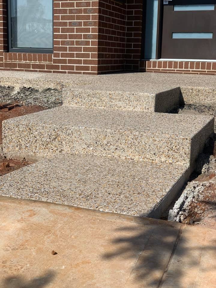Exposed aggregate steps at the front door of a brick home