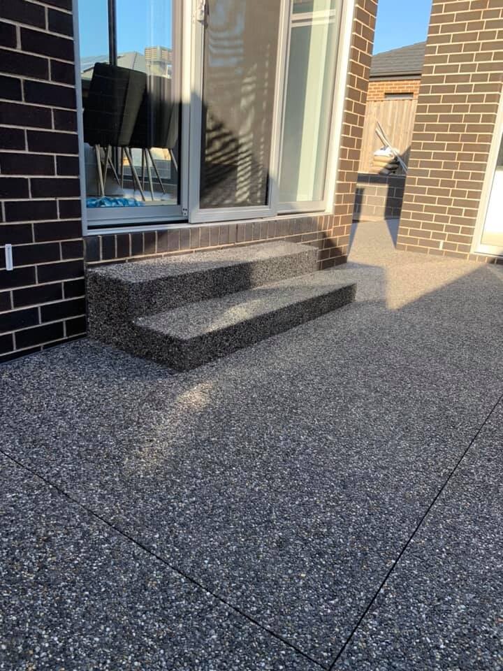 Exposed aggregate courtyard with steps up to a sliding door