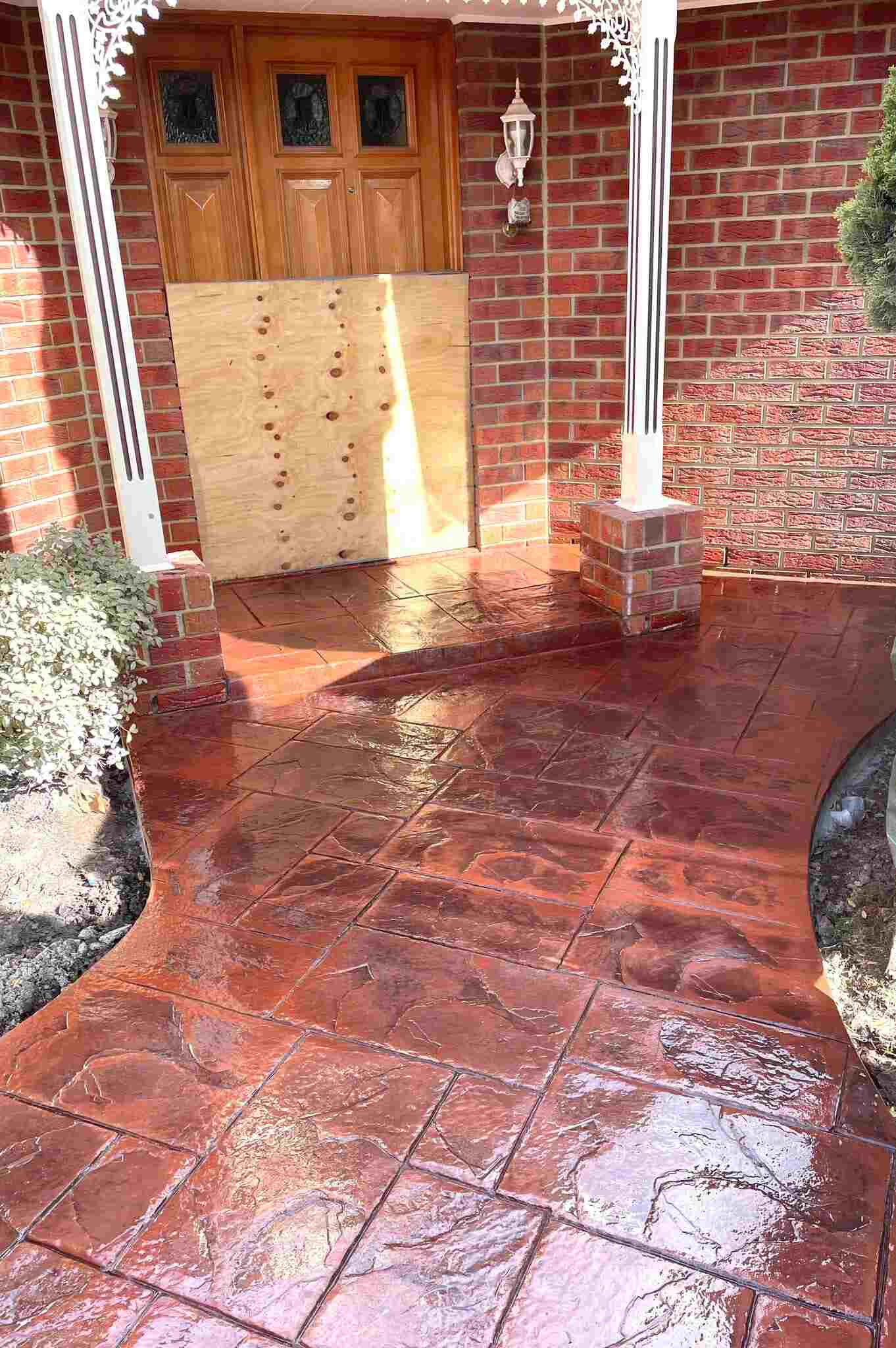 Glossy red stencilled concrete path at a brick home's front porch