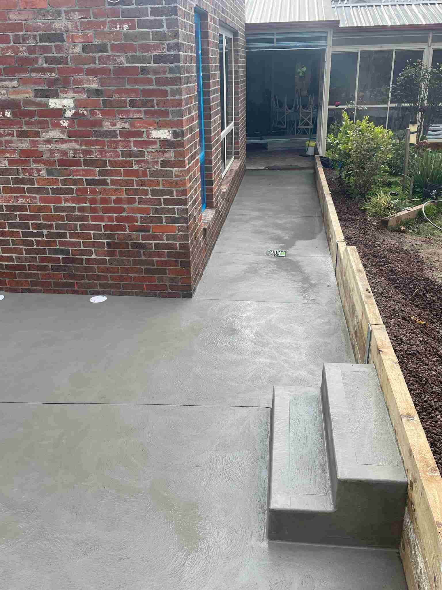 Freshly laid concrete area with steps beside a brick house