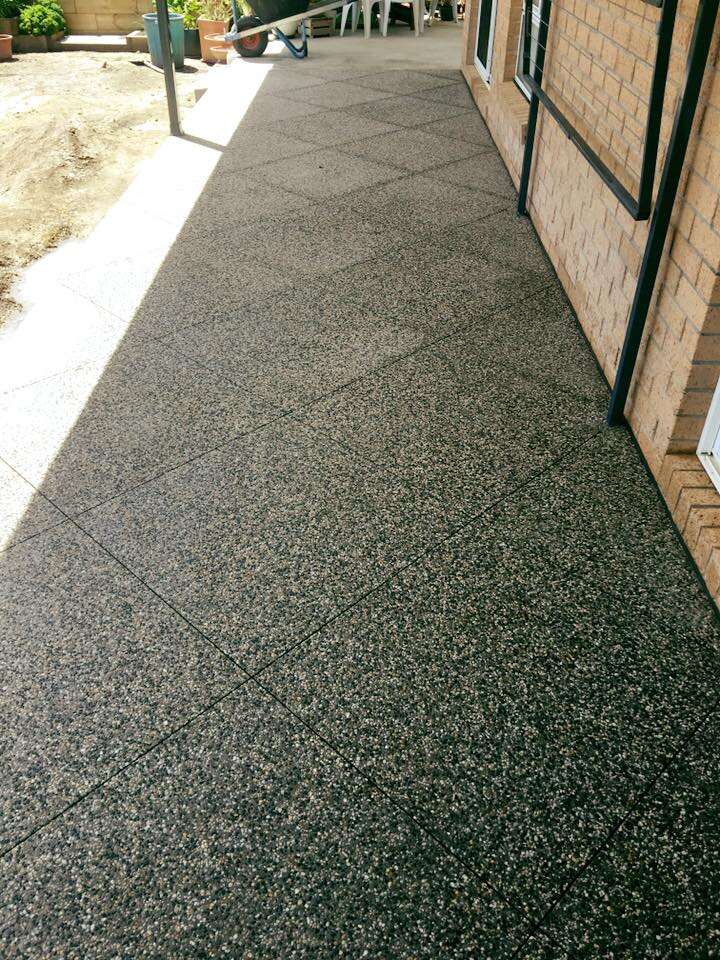 Exposed aggregate path along the side of a brick house