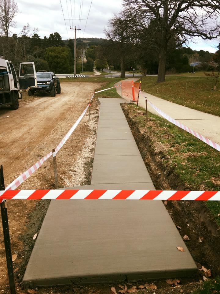 New concrete footpath behind barrier tape beside a road