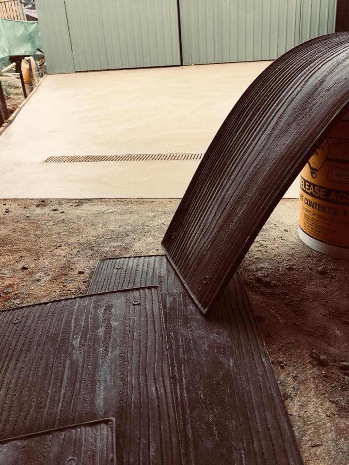 Stamping mat being lifted off fresh timber-look concrete