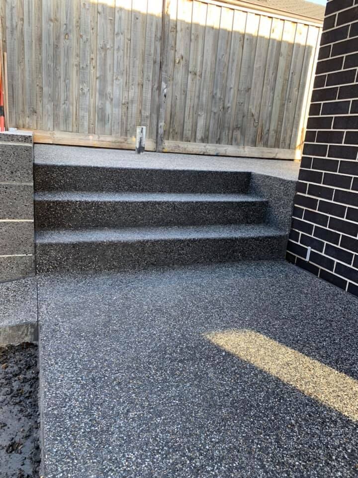Exposed aggregate steps and courtyard beside a dark brick wall