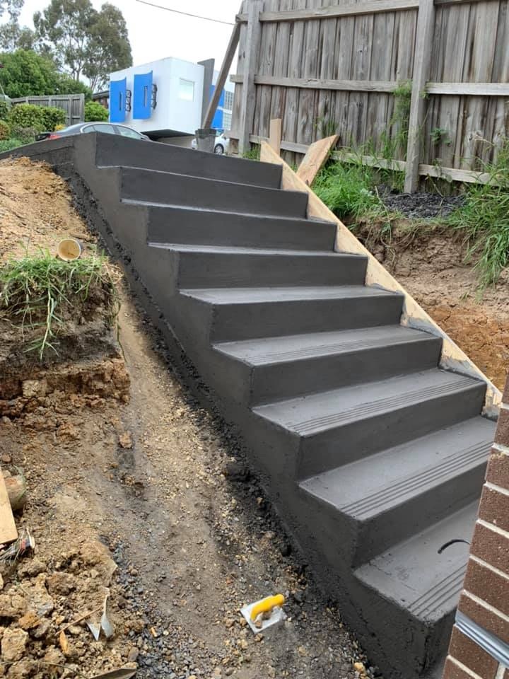 Concrete steps climbing a dug-out slope beside a timber fence