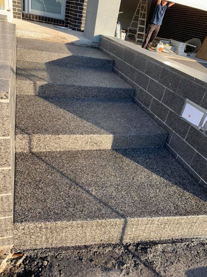 Exposed aggregate steps leading up beside a block wall